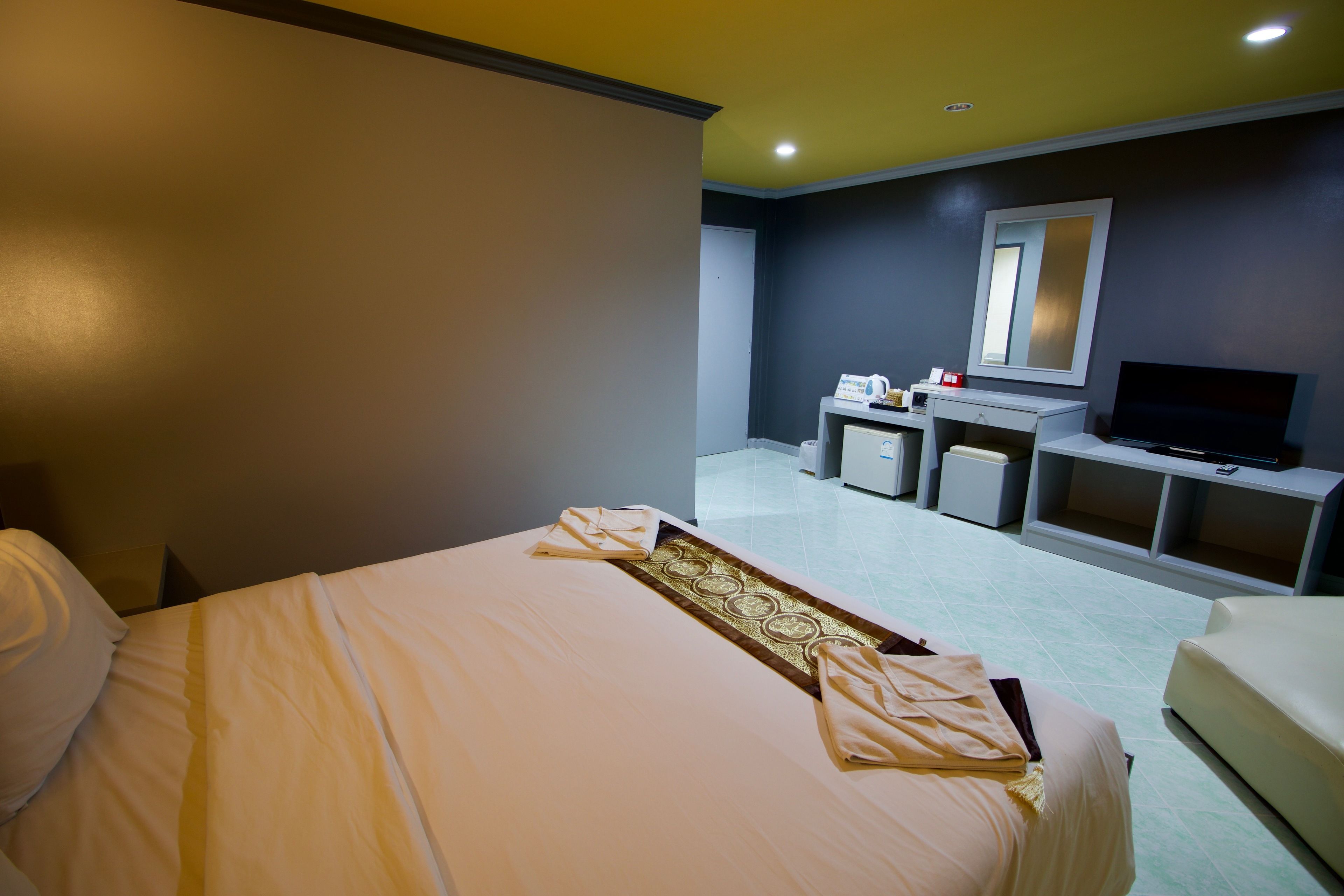 A hotel room with a bed, a desk, a TV, and a mirror.