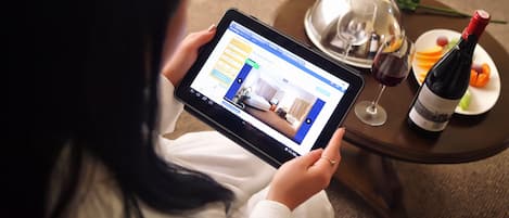 Eine Person benutzt ein Tablet mit einer Benutzeroberfläche zur Hotelbuchung.