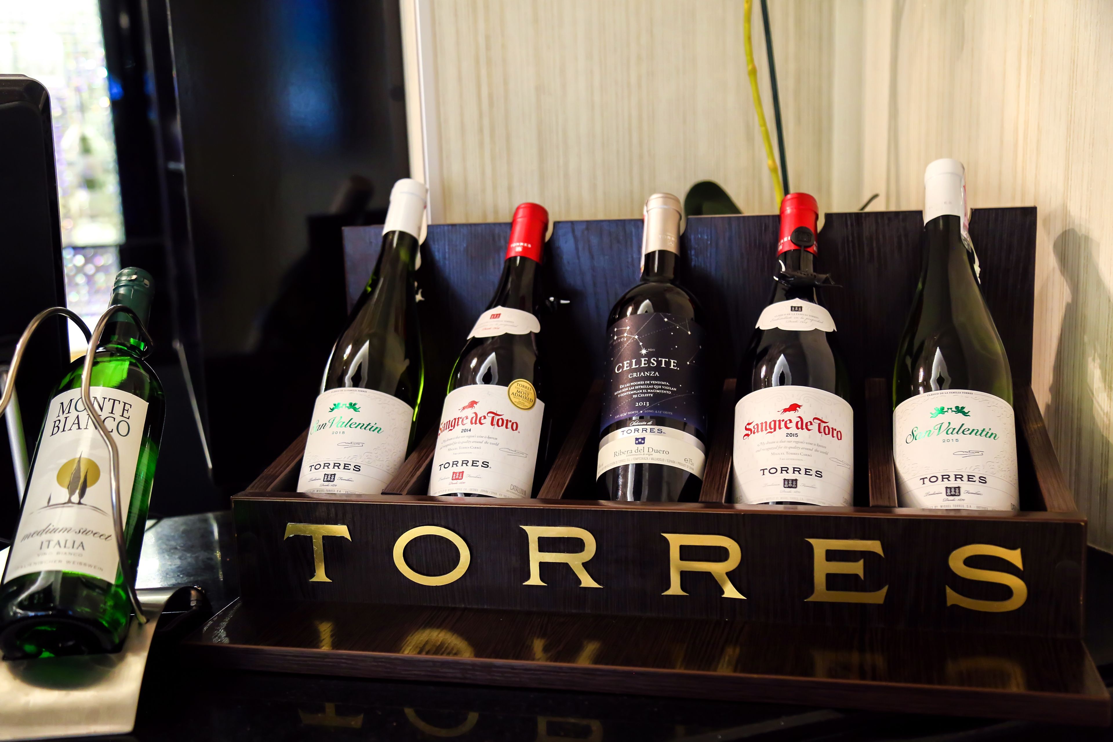 Un porte-bouteilles en bois contenant des bouteilles étiquetées « TORRES » et « Monte Bianco ».