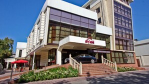 A modern hotel with a two-story structure, a covered entrance, and a car parked in the driveway. - City Hotel Bishkek (Bishkek)