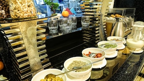 A buffet with various food items and utensils. - City Hotel Bishkek (Bishkek)