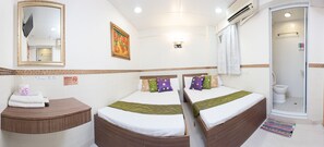 Una camera d'albergo con due letti, un bagno e una cabina doccia.