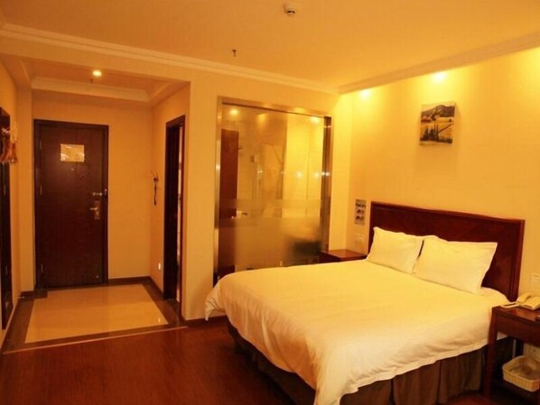 A hotel room with a bed, a nightstand, a telephone, and a door leading to a hallway.