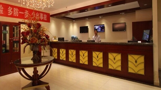 A hotel reception area with a chandelier, a reception desk, a TV screen, and a floral arrangement on a table. - GreenTree Inn Beijing East Yizhuang District Second Kechuang Street Express Hotel (Beijing)