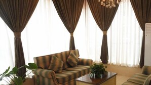 A living room with a sofa, a coffee table, and a potted plant. - GreenTree Inn Beijing East Yizhuang District Second Kechuang Street Express Hotel (Beijing)