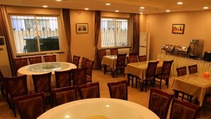 A dining area with round tables and chairs, large windows with curtains, and a view of the outside. - GreenTree Inn Beijing East Yizhuang District Second Kechuang Street Express Hotel (Beijing)