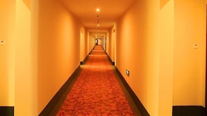 A long, narrow hotel corridor with a red carpet, yellow walls, and doors on both sides. - GreenTree Inn Beijing East Yizhuang District Second Kechuang Street Express Hotel (Beijing)