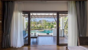 Quarto com vista para piscina e área de estar externa.