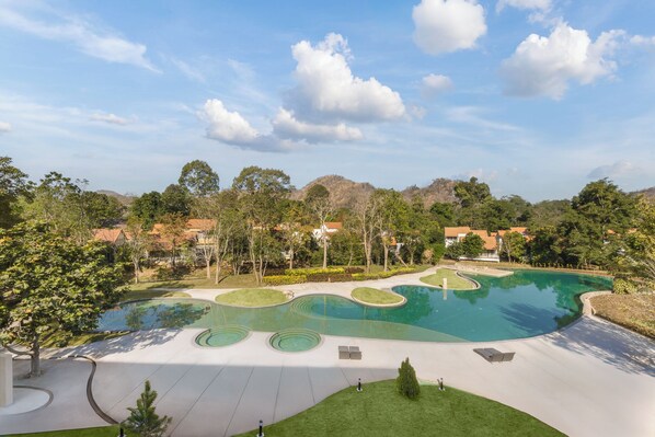 A landscaped area with a large pool, pathways, and surrounding greenery.