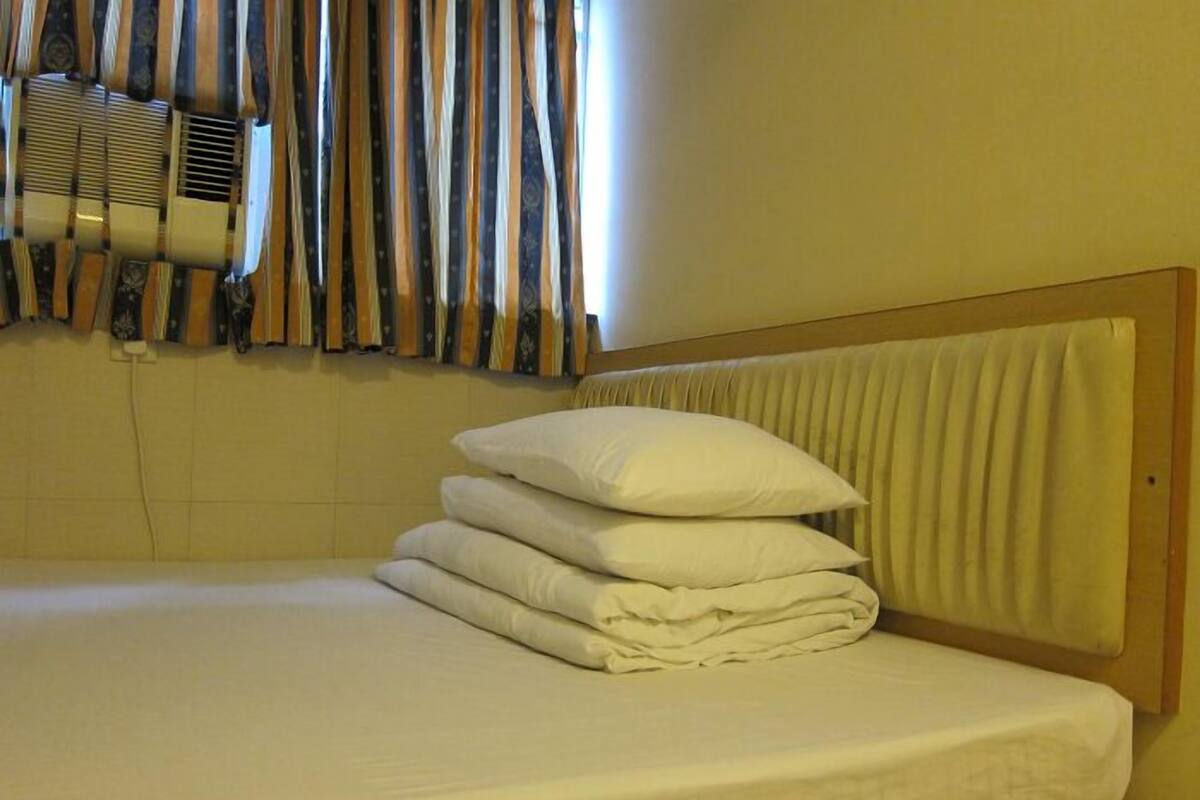 A neatly made bed with a wooden headboard and a window with curtains.