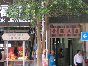 A street sign for Nathan Road with directional arrows and a shop entrance with a sign in a foreign language. - Hao's Inn (Kowloon)
