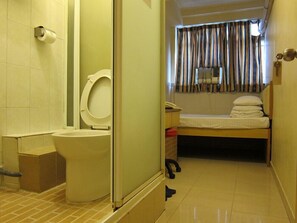 A small, compact bathroom with a toilet, a sink, and a shower area. - Hao's Inn (Kowloon)
