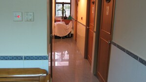 A hotel corridor with wooden doors, a bench, and a bed in the background. - Hao's Inn (Kowloon)