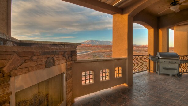 A covered outdoor area with a stone fireplace, a grill, and a view of mountains. - Coral Springs Resort (Hurricane)