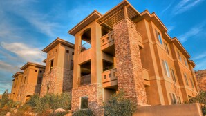 A multi-story hotel with stone and stucco exterior, balconies, and a clear sky. - Coral Springs Resort (Hurricane)