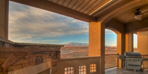 A covered outdoor area with a stone wall, a grill, and a view of mountains. - Coral Springs Resort (Hurricane)