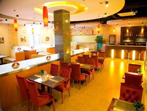 A restaurant with red upholstered chairs, a counter with a logo, and a bar area. - GreenTree Inn Jiangsu Suzhou Kunshan Huaqiao Household Building Materials City Shell Hotel (Suzhou)