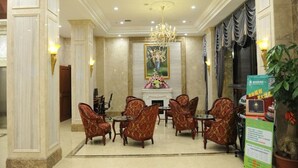 A lobby with marble flooring, a chandelier, patterned armchairs, a fireplace, and a large painting. - GreenTree Inn Meizhou Meijiang District Wanda Plaza Hotel (Meizhou)