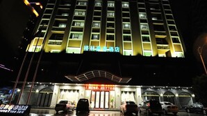 A hotel with multiple floors, a prominent entrance with a red sign, and several cars parked in front. - GreenTree Inn Meizhou Meijiang District Wanda Plaza Hotel (Meizhou)