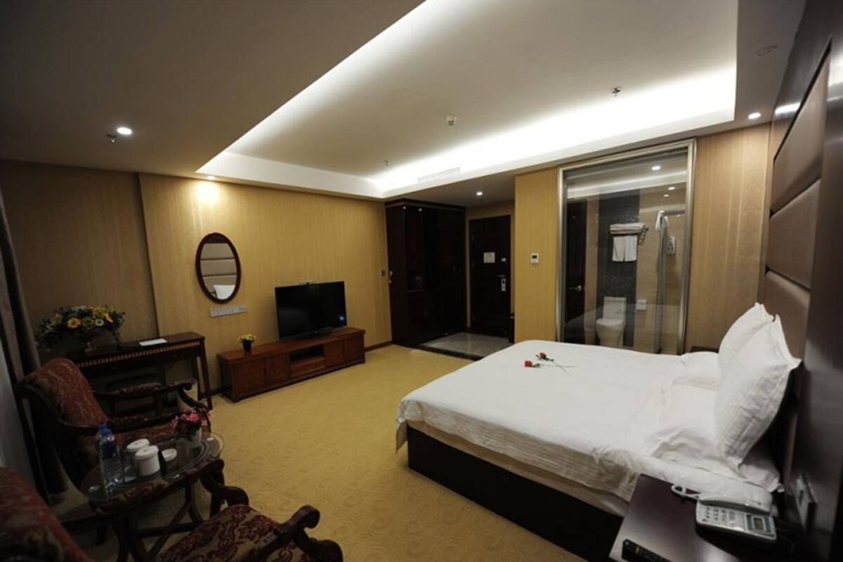 A hotel room with a bed, a TV, a desk, a chair, and a bathroom.