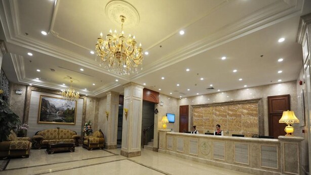A hotel lobby with a reception desk, seating area, chandelier, and a large painting on the wall. - GreenTree Inn Meizhou Meijiang District Wanda Plaza Hotel (Meizhou)