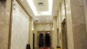 A hotel lobby with marble walls, a red carpet, and an elevator. - GreenTree Inn Meizhou Meijiang District Wanda Plaza Hotel (Meizhou)