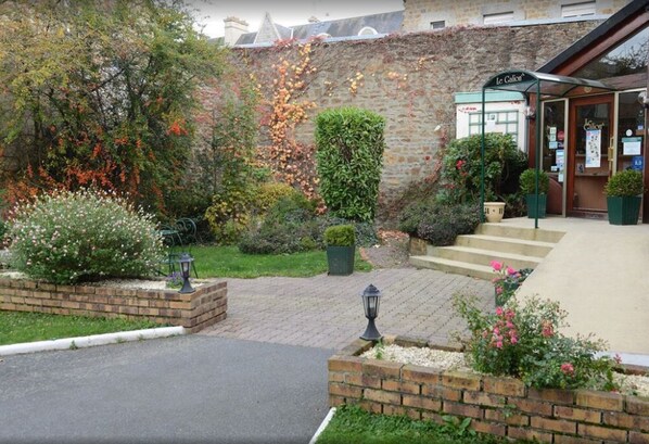 A brick building with a garden entrance, steps leading to a door labeled "Le Calv".