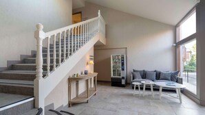 Interior moderno com escada, máquina de vendas e área de estar com vista.