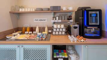 A breakfast buffet setup with various food items, a coffee machine, and neatly arranged kitchenware.