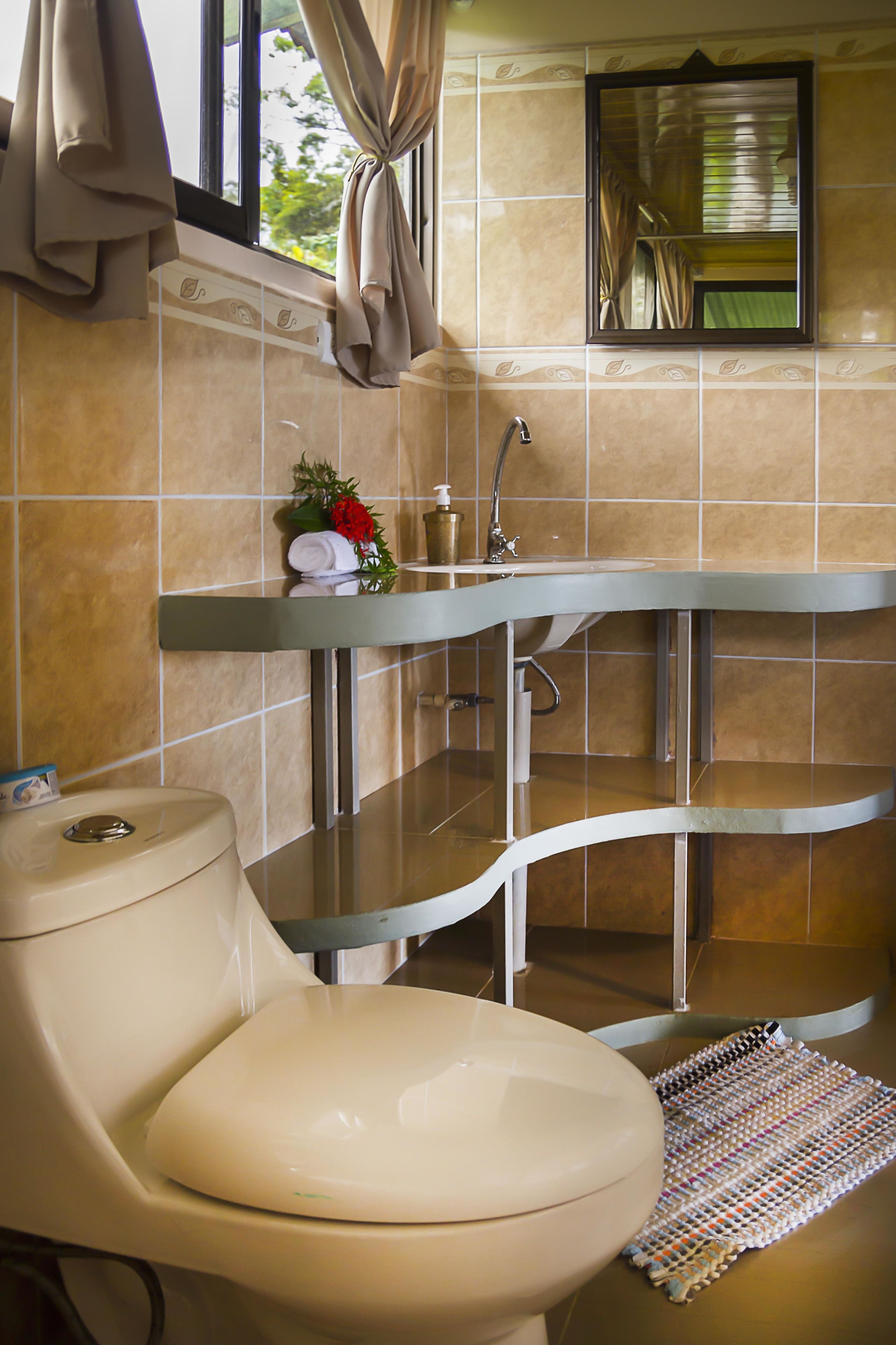 A bathroom with a toilet, sink, and mirror.