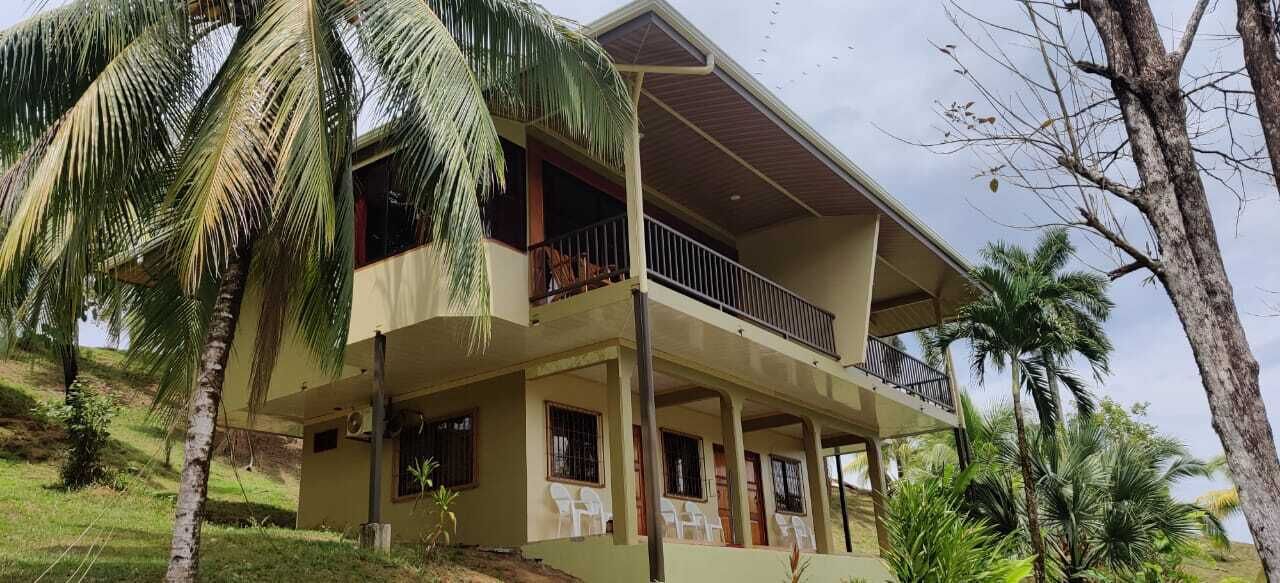 A two-story building with a balcony on the upper floor, surrounded by palm trees.