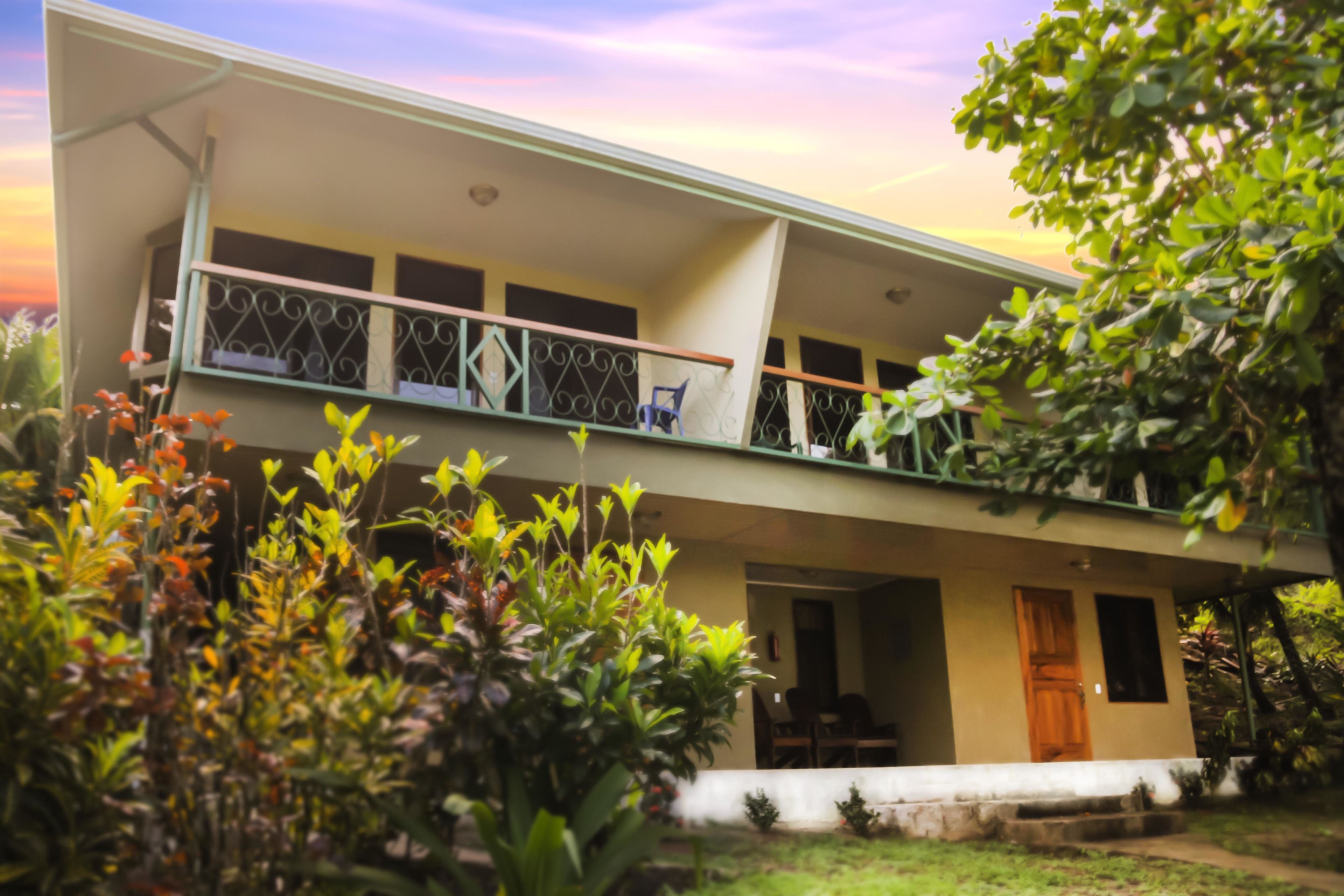 A two-story building with a balcony, a door, and a small porch area.