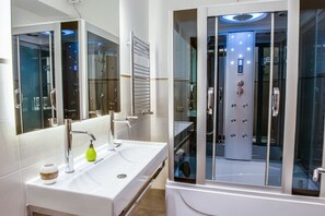 A modern bathroom with a large mirror, two sinks, and a glass-enclosed shower area. - Lh Royal Suites (Rome)