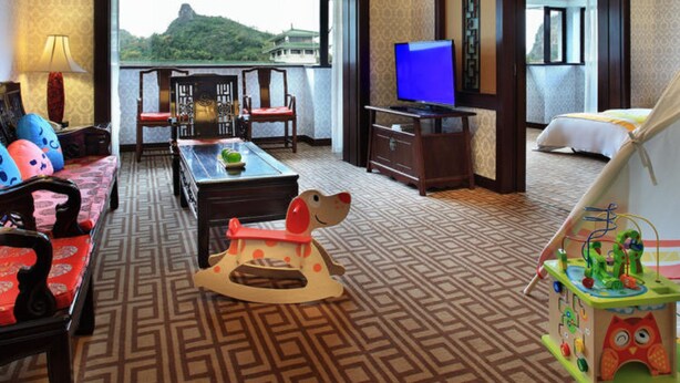 A hotel room with a large window, a television, a wooden coffee table, a sofa, and a tent-like structure. - Guilin Park Hotel (Guilin)