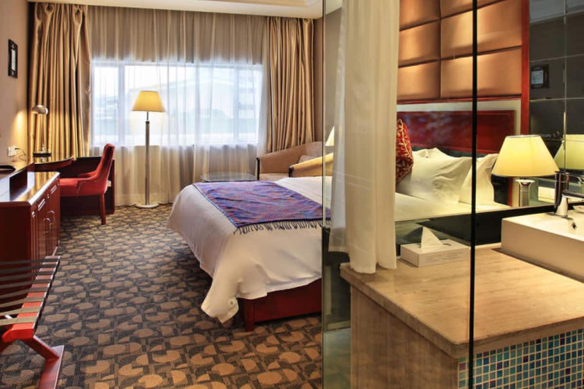 A hotel room with a bed, a desk, a chair, and a bathroom with a mirror.