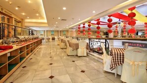 A spacious hotel lobby with a long buffet line, neatly arranged tables with checkered tablecloths, and red lanterns hanging from the ceiling. - Guilin Park Hotel (Guilin)