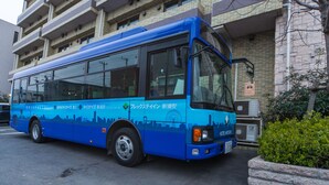Un autobús azul estacionado frente a un edificio con varios balcones.