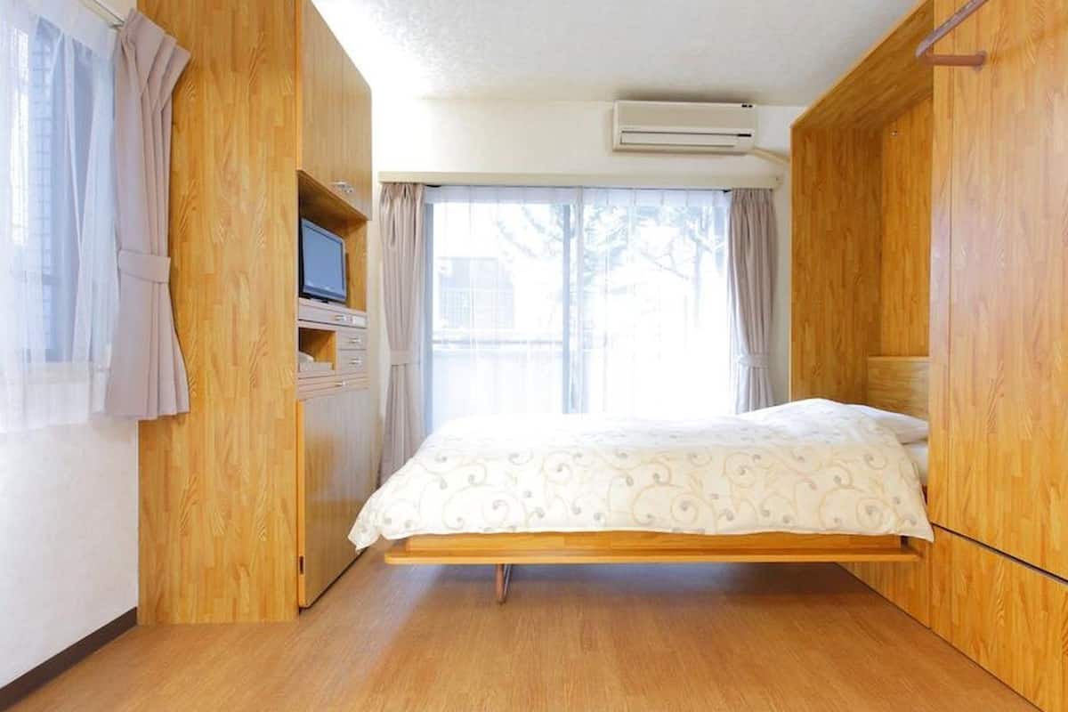 Una habitación con una cama, paredes de madera, un televisor y un equipo de aire acondicionado.