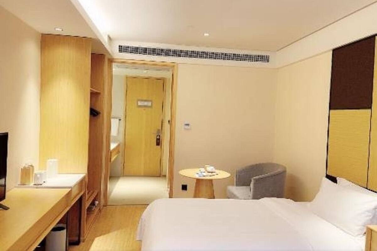 Une chambre d’hôtel comprenant un lit, un bureau, une chaise, une petite table et une armoire.