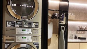 A commercial laundry machine with a control panel, a dryer, and a refrigerator in a kitchen setting. - Ji Hotel (Shanghai)