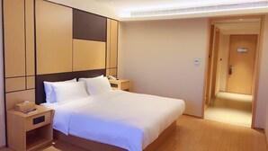 A hotel room with a large bed, bedside tables, a phone, and a door leading to another room. - Ji Hotel (Shanghai)