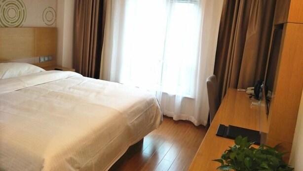 A hotel room with a bed, a desk, a chair, and a window with curtains. - Greentree Inn Tianjin Dongli Development Zone Expr (Tianjin)