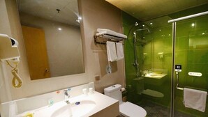 Une salle de bain moderne avec un grand miroir, un lavabo, des toilettes et une douche séparée par une paroi en verre.