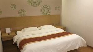 A neatly made bed with a white and brown bedspread, a wooden headboard, and a nightstand with a lamp and a small item on it. - Greentree Inn Tianjin Dongli Development Zone Expr (Tianjin)