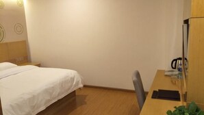 A hotel room with a bed, bedside table, desk, chair, and a potted plant. - Greentree Inn Tianjin Dongli Development Zone Expr (Tianjin)