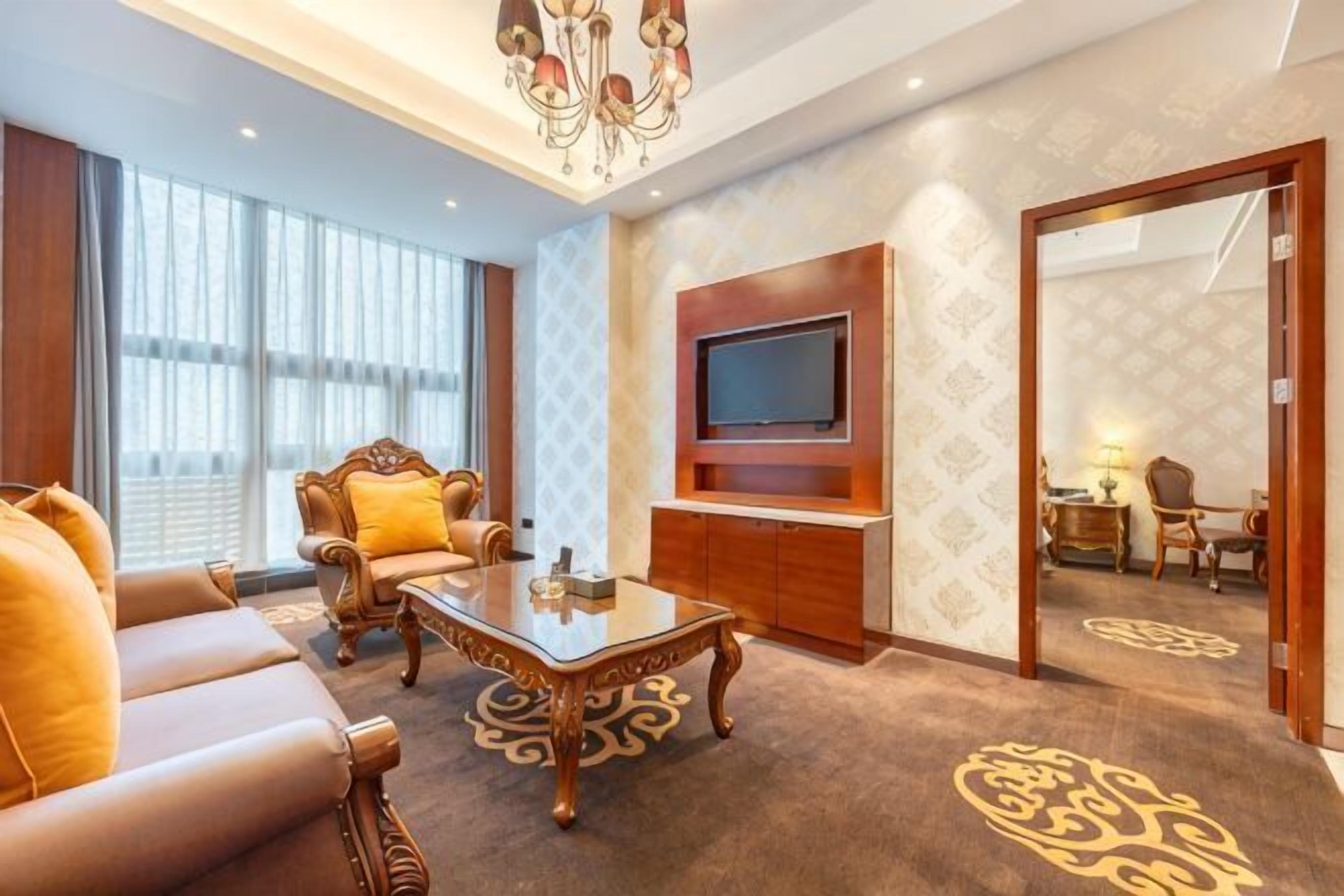 A living room with a sofa, coffee table, TV, and patterned carpet.