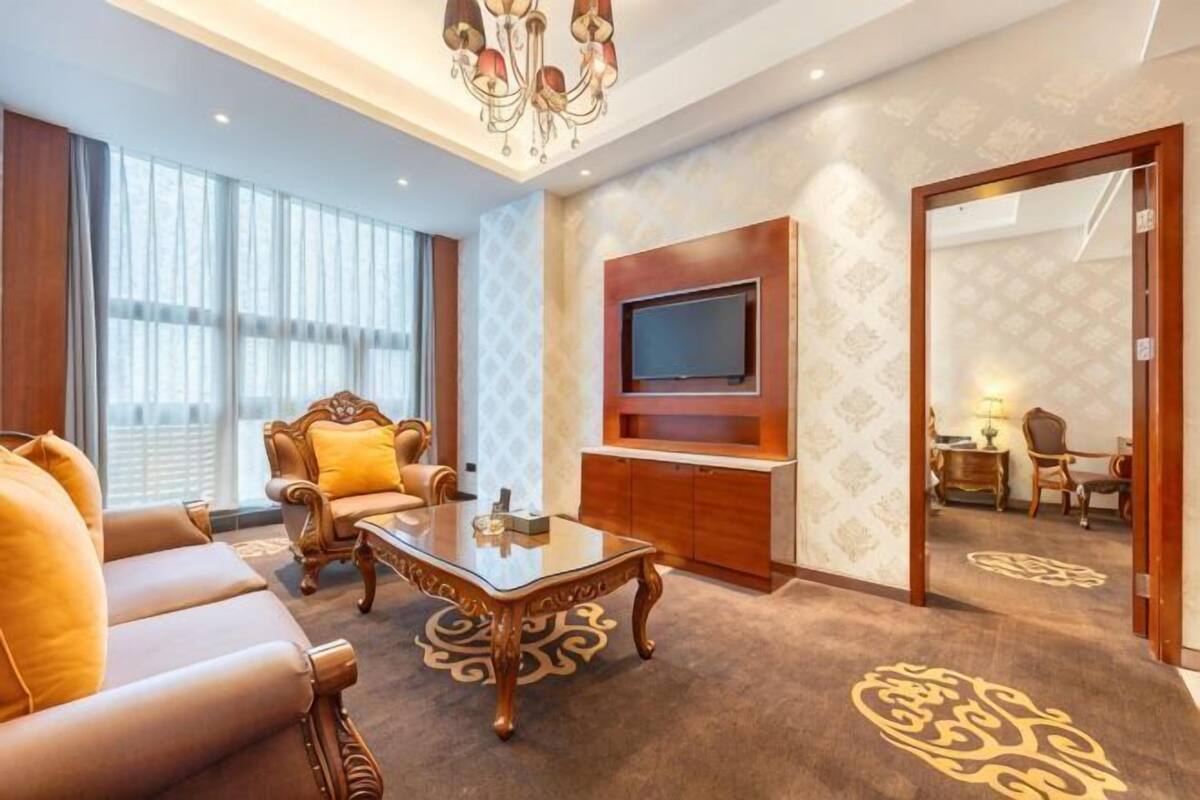 A living room with a sofa, coffee table, TV, and patterned carpet.