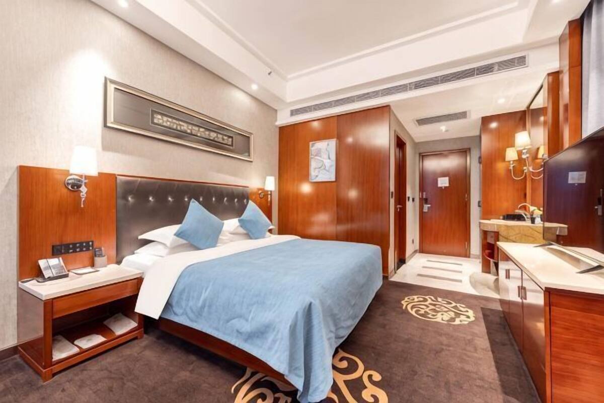 A hotel room with a bed, bedside table, lamp, and a mirror.
