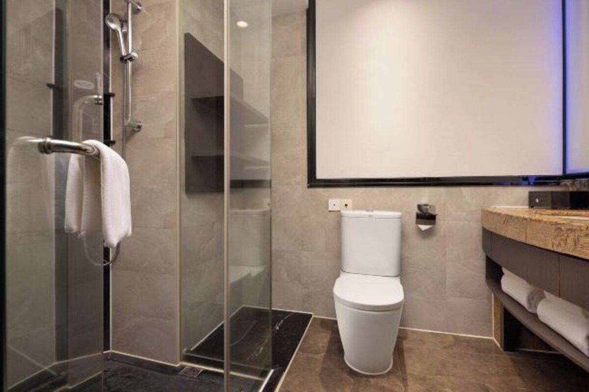 A modern bathroom with a glass shower enclosure, a white toilet, and a marble-tiled floor.
