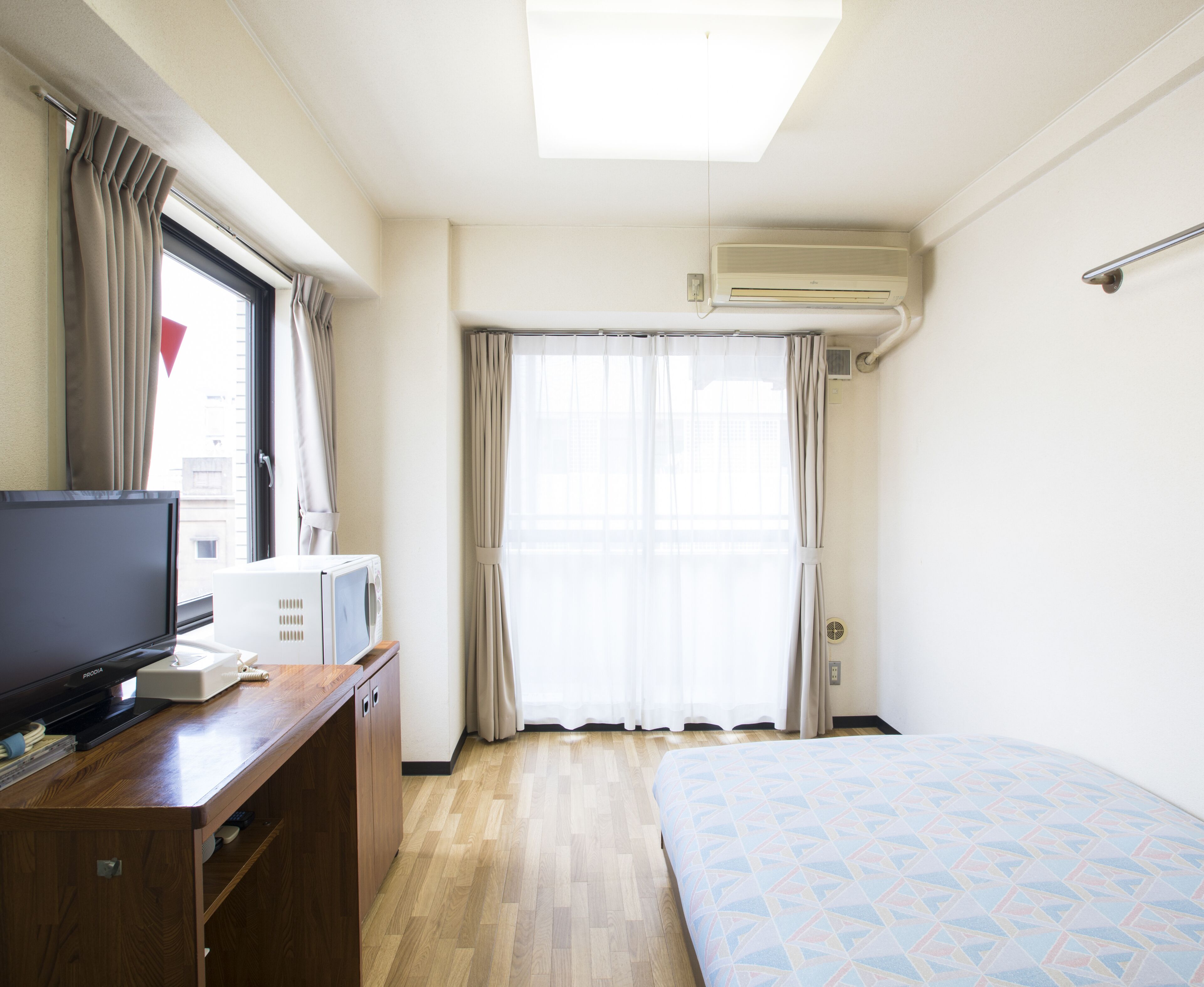 Une chambre d’hôtel équipée d’un lit, d’un bureau avec une télévision, d’un four à micro-ondes et d’un appareil de climatisation.